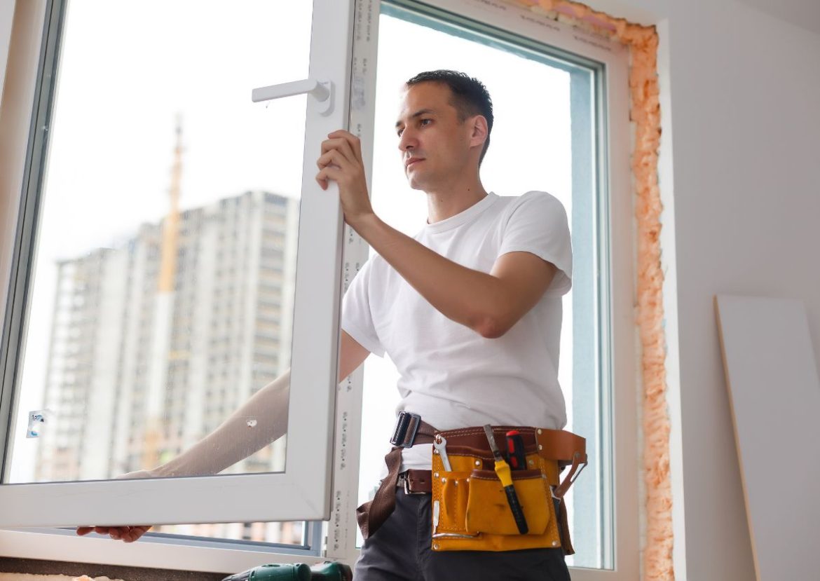 Homme installant une fenêtre en PVC, travaux de menuiserie et rénovation.