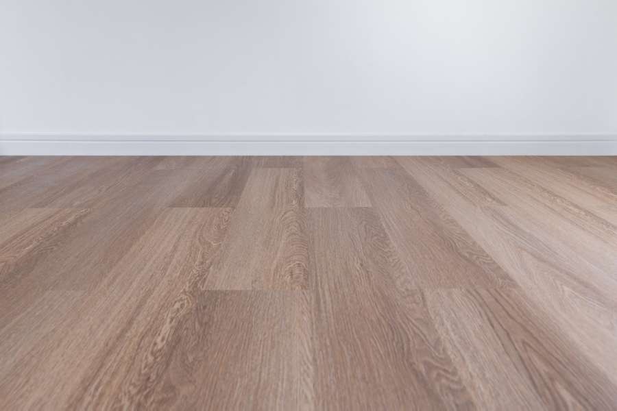 Un magnifique plancher en bois aux lattes claires s'étendant devant un mur blanc épuré